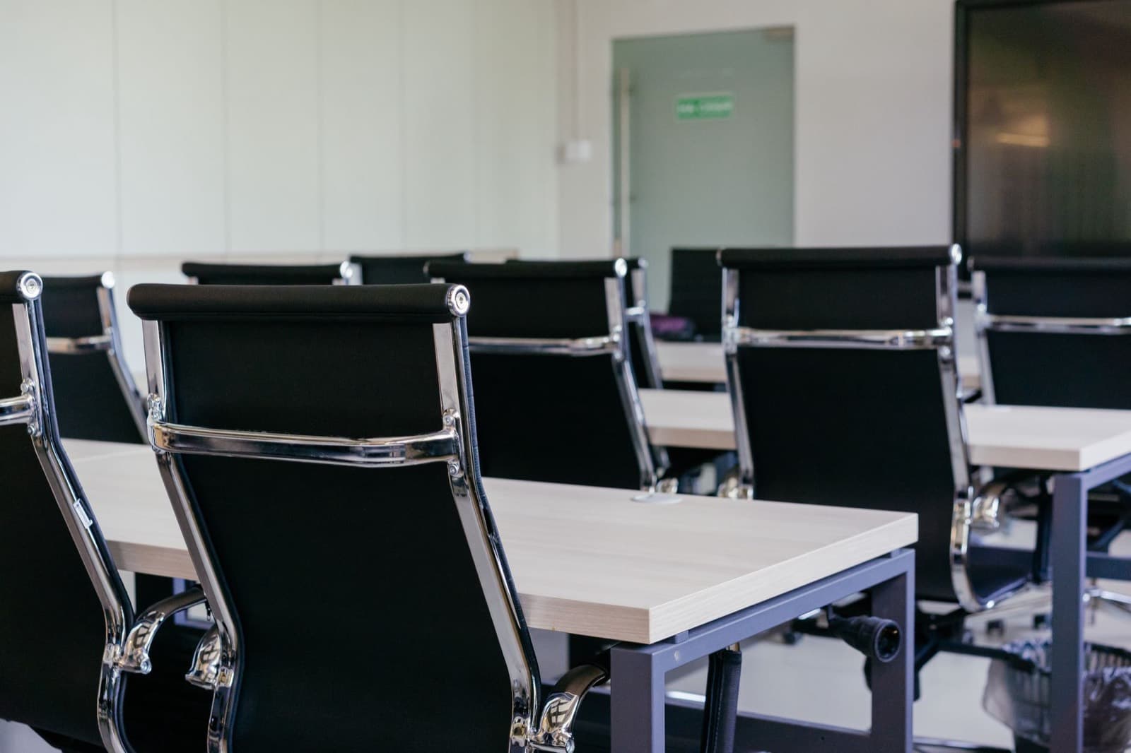 A row of empty black meeting chairs along a boardroom table