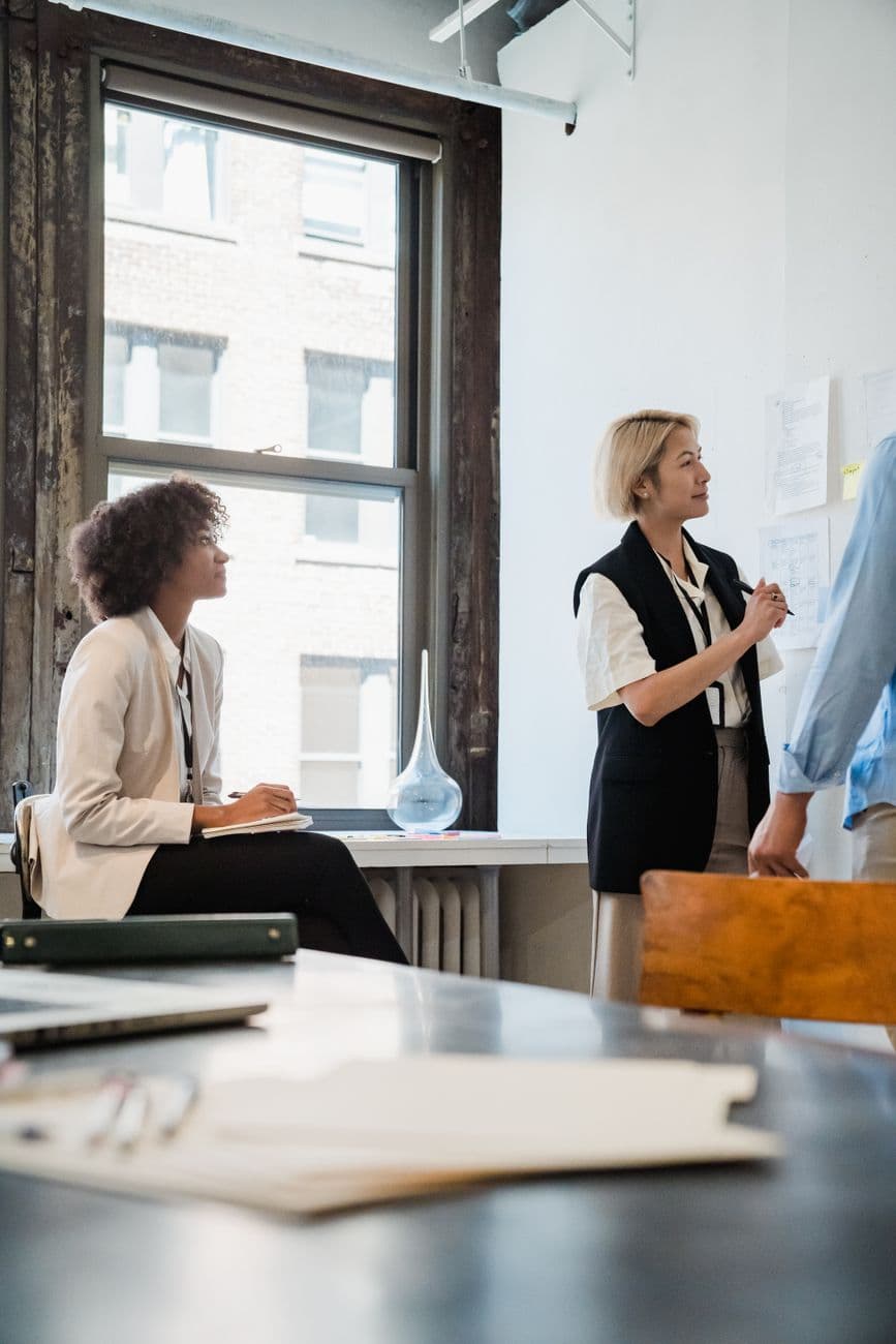 Two finance professionals talking beside an office window